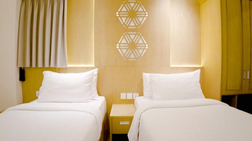 雅加达UNUMA HOTEL的两张睡床彼此相邻,位于一个房间里