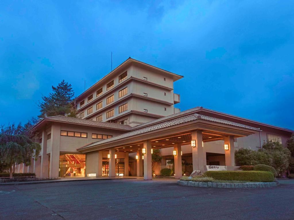 芦原市Yukai Resort Premium Seiunkaku的酒店大楼前面设有停车场
