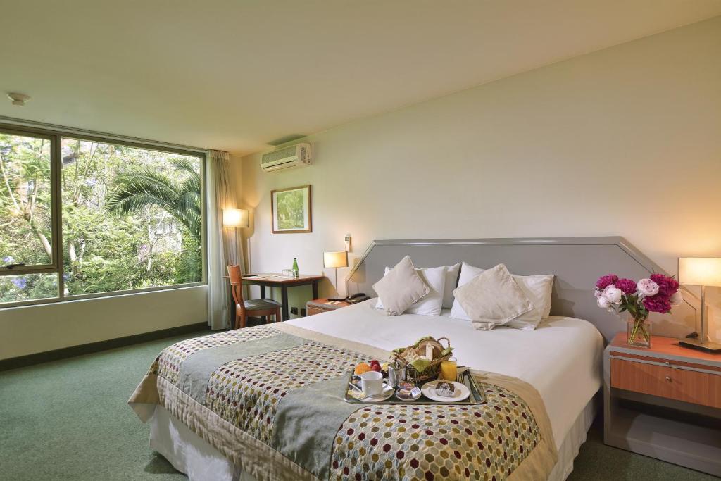圣地亚哥埃尔博斯克欧洲酒店的一间卧室配有一张床,上面放着一个食物托盘