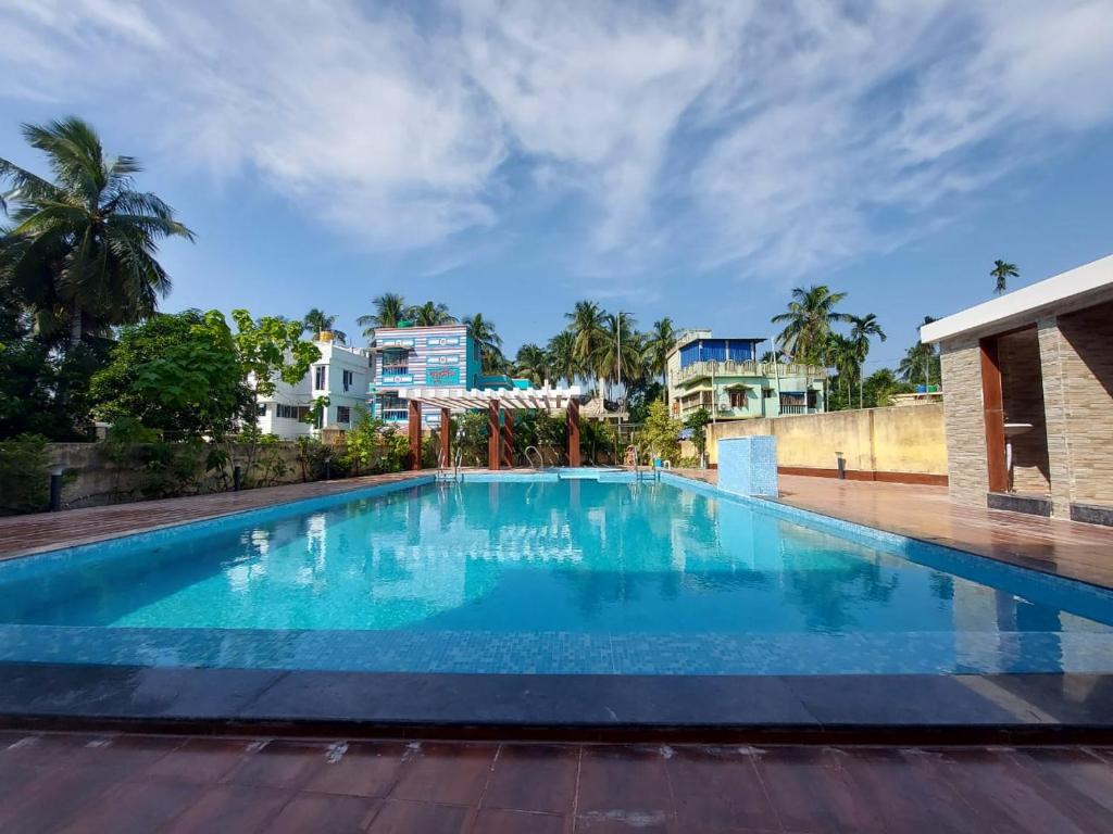 迪卡ICONIC Hotel Digha的一个大型蓝色游泳池,其建筑背景为: