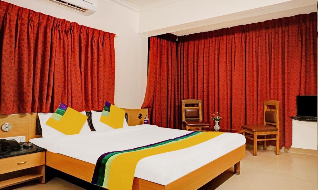 浦那Itsy By Treebo - Crown Inn的一间卧室配有大床和红色窗帘