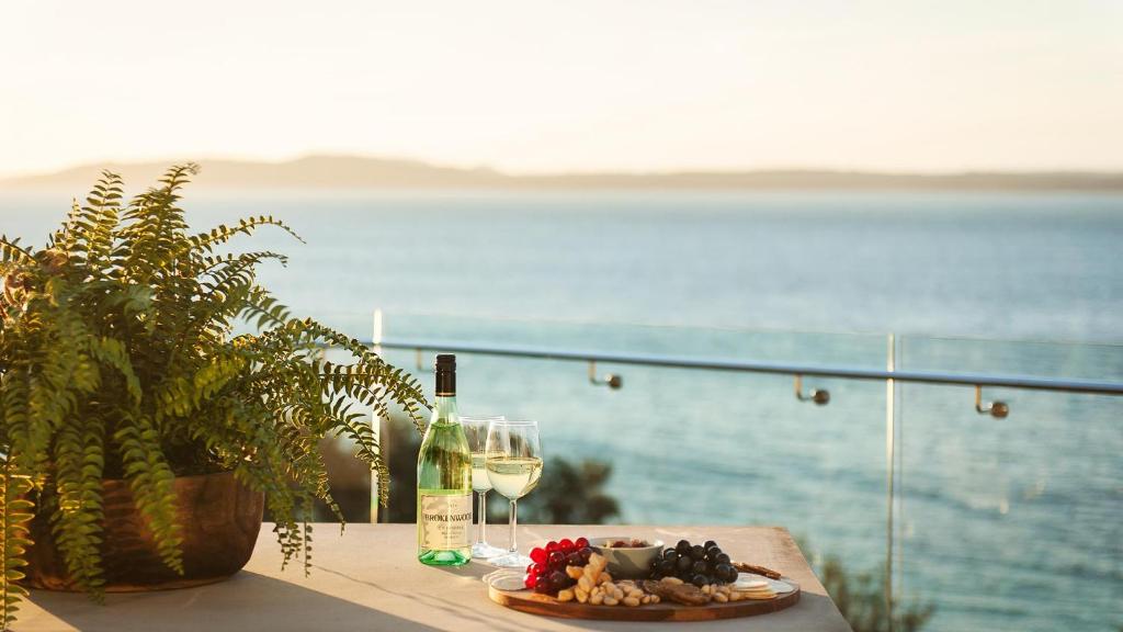 尼尔森湾Riviera - Panoramic Water Views In The Heart Of Nelson Bay的一张桌子,上面放着一盘食物和一杯葡萄酒