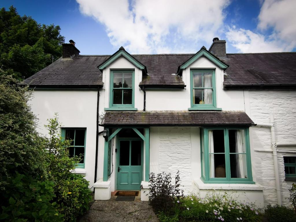 LlanfyrnachWellstone Cottages - Jasmine的白色的房子,设有绿色的门和窗户