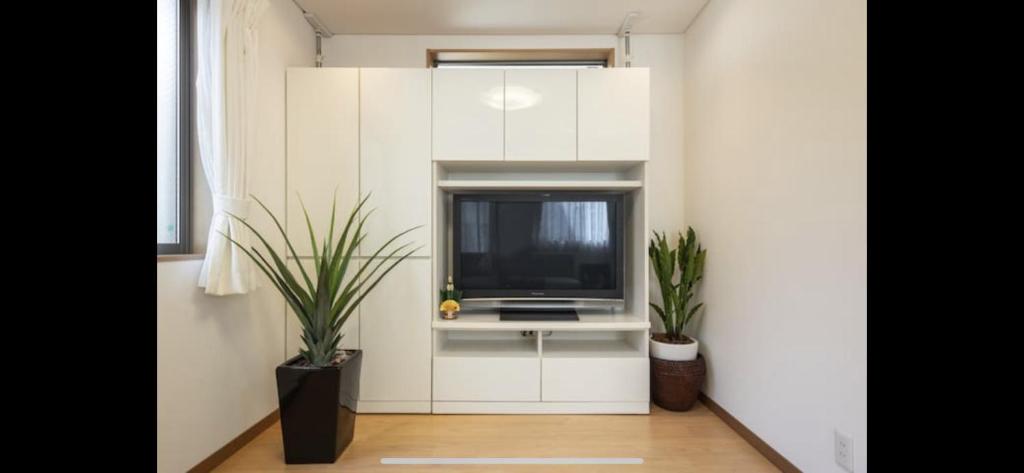 东京田端民泊ー田端ハウス的一间客厅,客厅配有白色橱柜内的电视