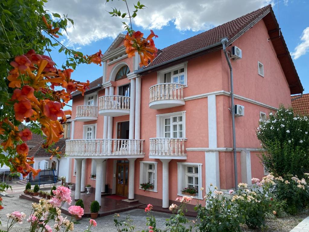 百乐费利克斯Pensiunea Ana的一座大型粉红色建筑,设有阳台和鲜花