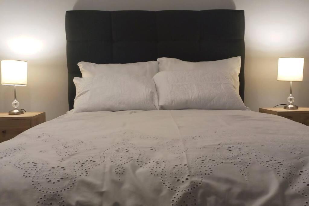 利马Gorgeous Private Studio LIMA-Own Bathroom-Near Airport的一间卧室配有一张带白色床单和两盏灯的床。