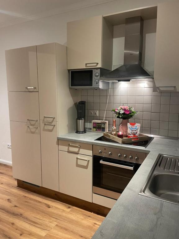 埃姆登Ferienwohnung Ostfriesenherz Emden的厨房配有白色橱柜、炉灶和水槽。
