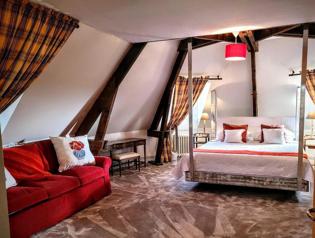 Saint-Aubin-de-LuignéLa Coulee Verte的一间卧室配有一张床和一张红色的沙发