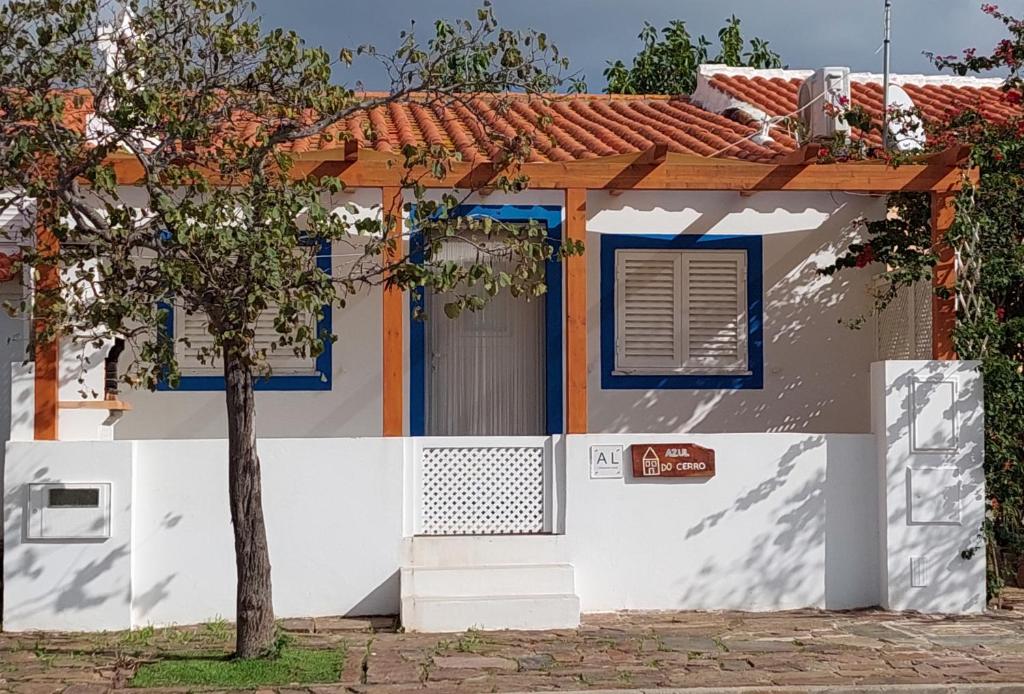 CampeirosCasa Azul do Cerro的白色的房子,有蓝色的窗户和树