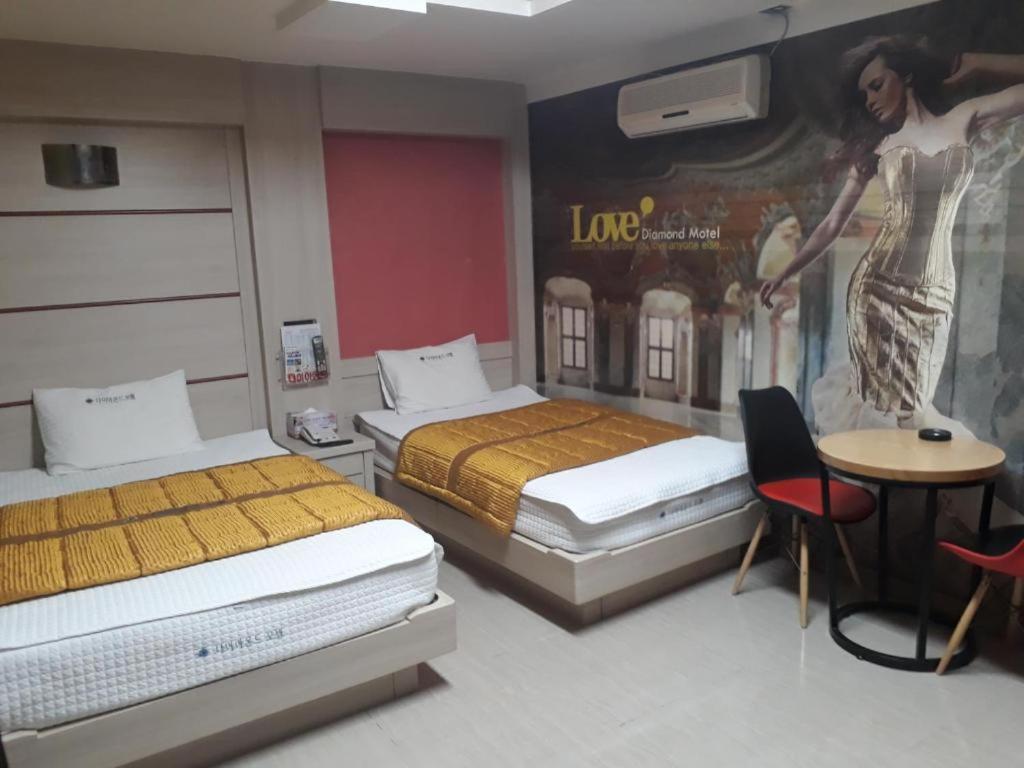 泗川Diamond Motel的一间设有两张床的客房,墙上挂着一幅画