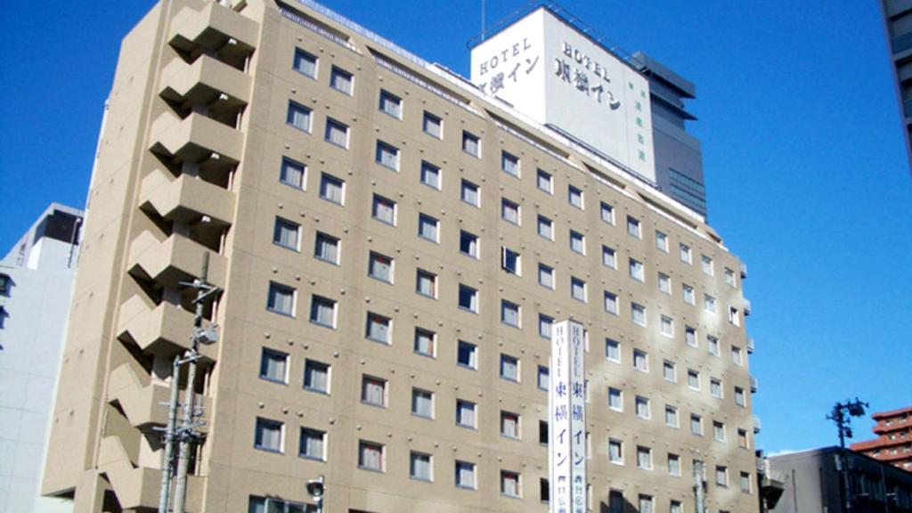 仙台Toyoko Inn Sendai Nishi-guchi Hirose-dori的一座高大的建筑,上面有标志