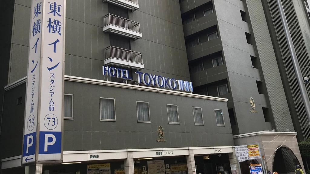 横滨Toyoko Inn Yokohama Stadium Mae No 2的一座高大的建筑,旁边有一个标志