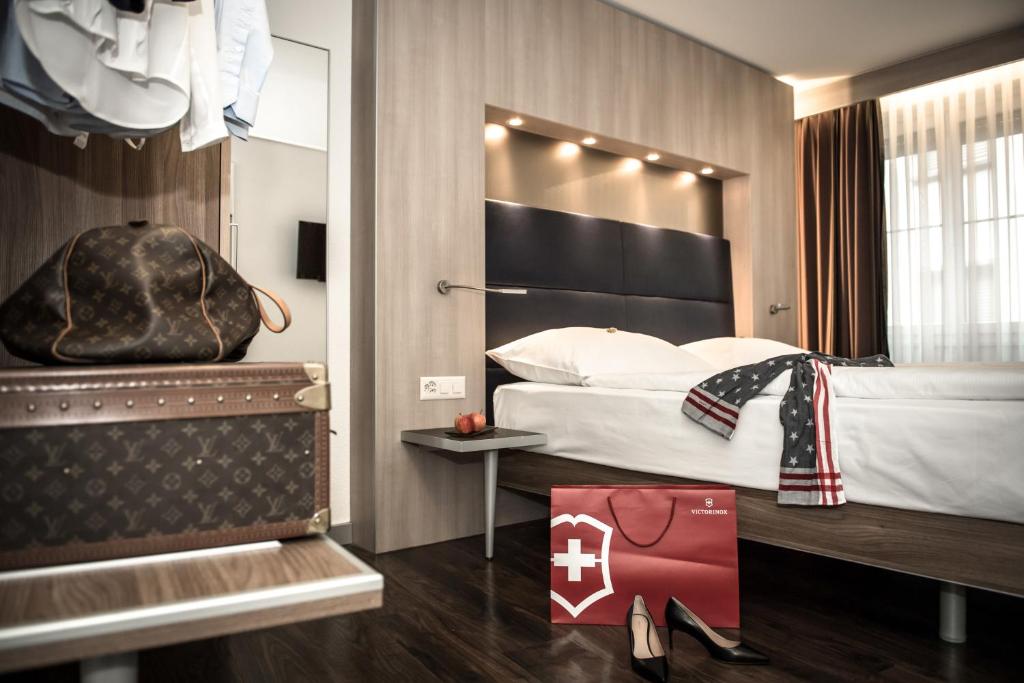 苏黎世Hotel Alexander Zurich Old Town的一间酒店客房,配有一张床铺和一个袋子