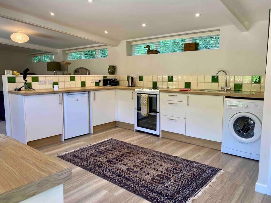 布里德波特Little Innsacre的厨房配有白色橱柜、洗衣机和烘干机
