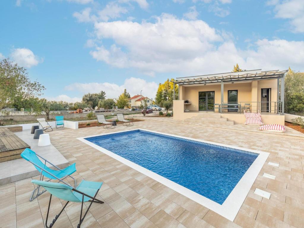 比利切Modern holiday home in Bilice with private pool的一个带椅子的游泳池以及一座房子