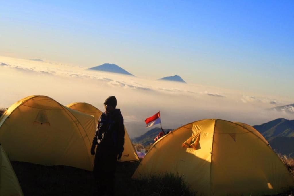 BaturajaBatur Sunset Sunrise camping的站在三个帐篷前的人