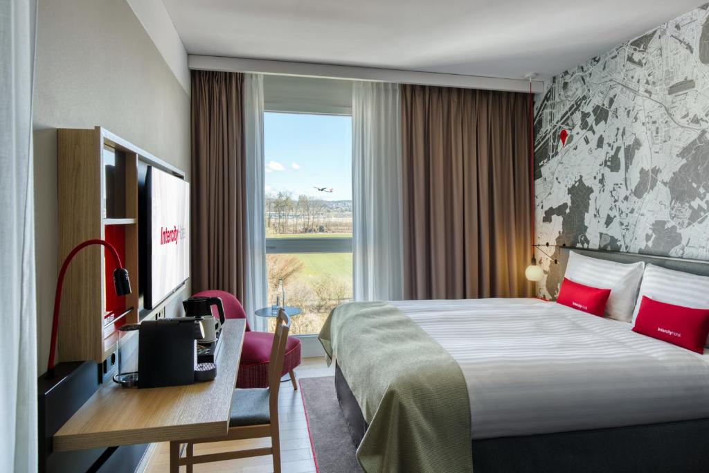 吕姆朗IntercityHotel Zürich Airport的配有一张床、一张书桌和一扇窗户的酒店客房