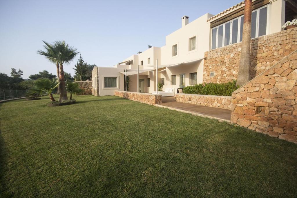 圣塔格鲁迪斯Attractive Ibiza Villa Can Tierra 6 Bedrooms Phenomenal Country and Mountain Views Santa Gertrudis的一座石墙和草地庭院的房子