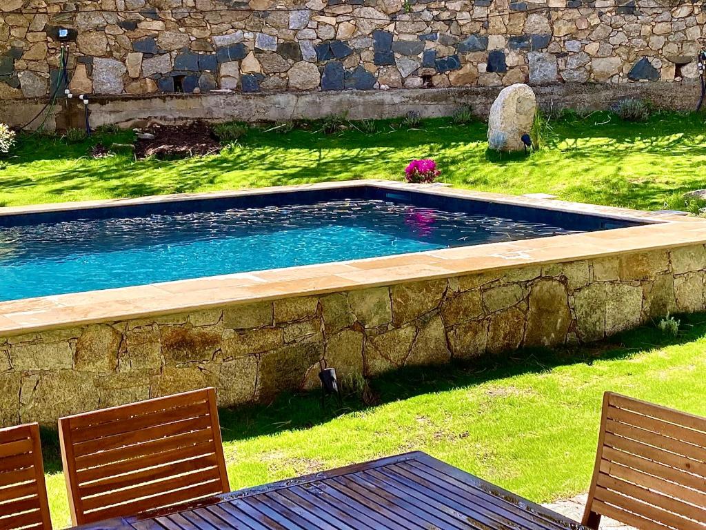 卡尔维Villa La Giraudière的一个带两把椅子和石墙的游泳池