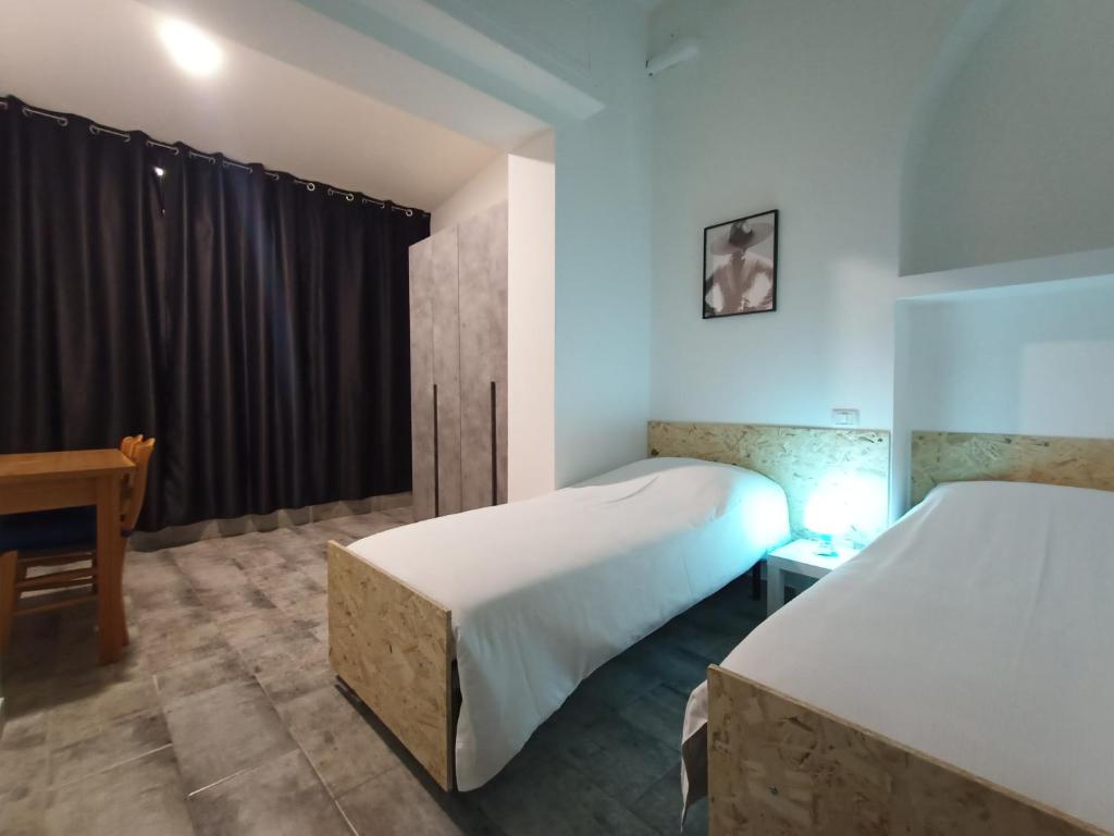 格拉索比奥Airport Boulevard Guesthouse的一间卧室设有两张床、一张桌子和一个窗口。