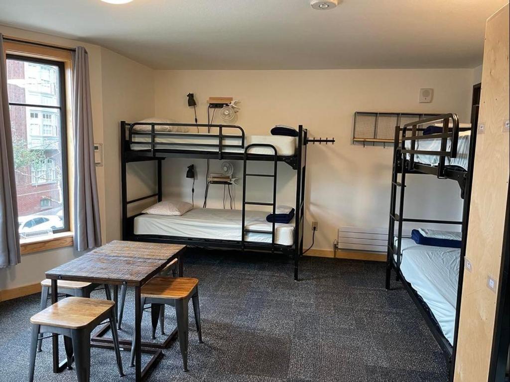 波特兰Northwest Portland Hostel的客房设有三张双层床和一张桌子。