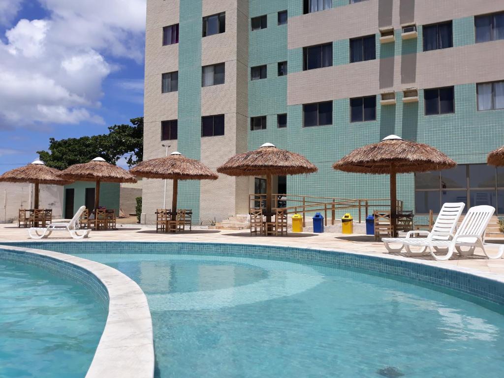 马塞约Apartamento com 2 quartos de FRENTE PARA O MAR的酒店前的游泳池配有椅子和遮阳伞