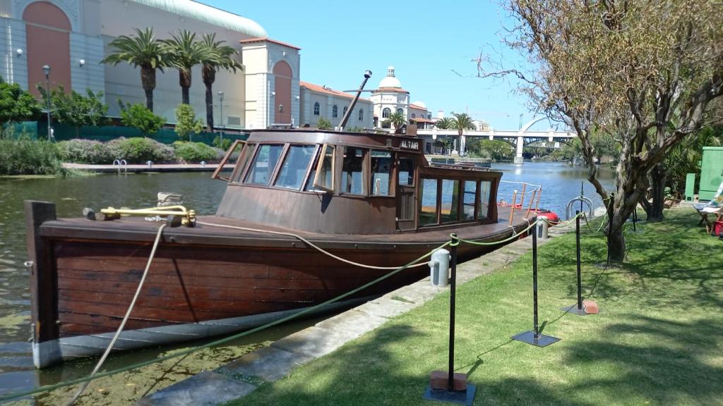 开普敦ALTAIR . Wooden Boat . Cape Town的船停靠在水中,靠近一座建筑