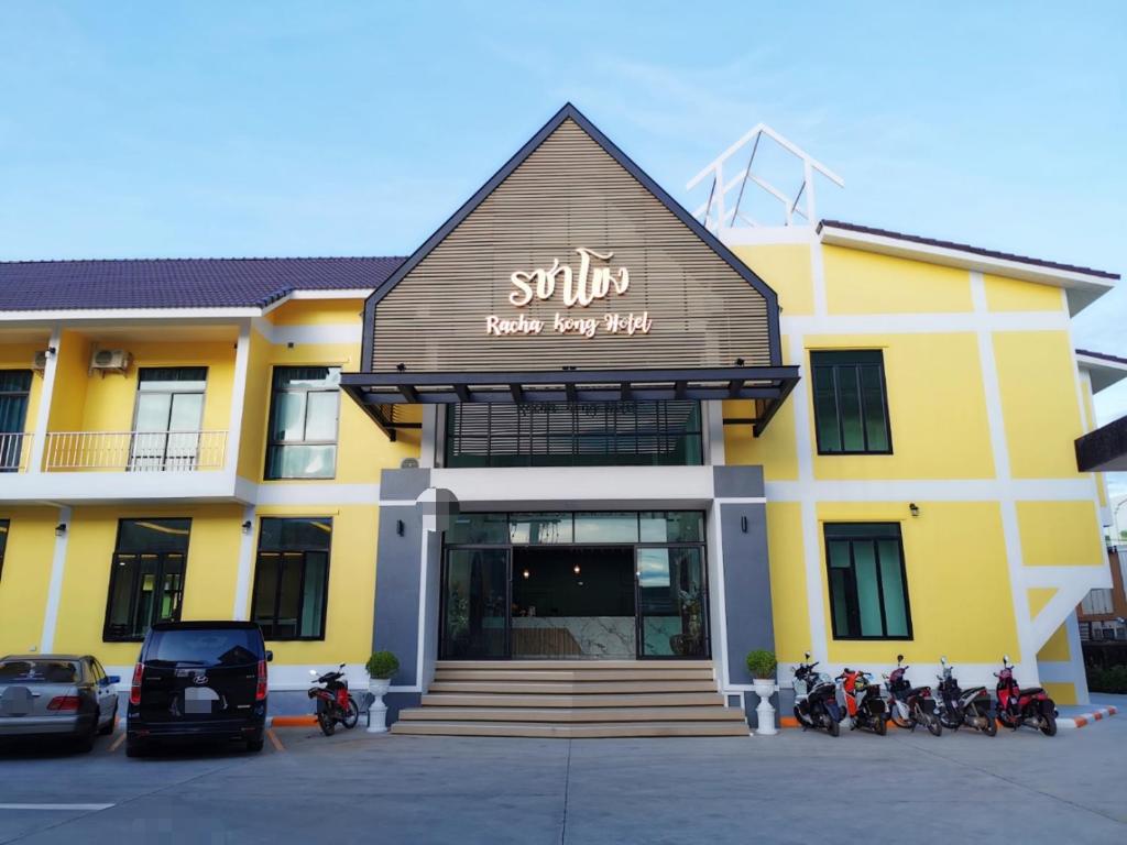那空拍侬府โรงแรมรชาโขง Racha Khong Hotel的停在前面的黄色建筑,有摩托车