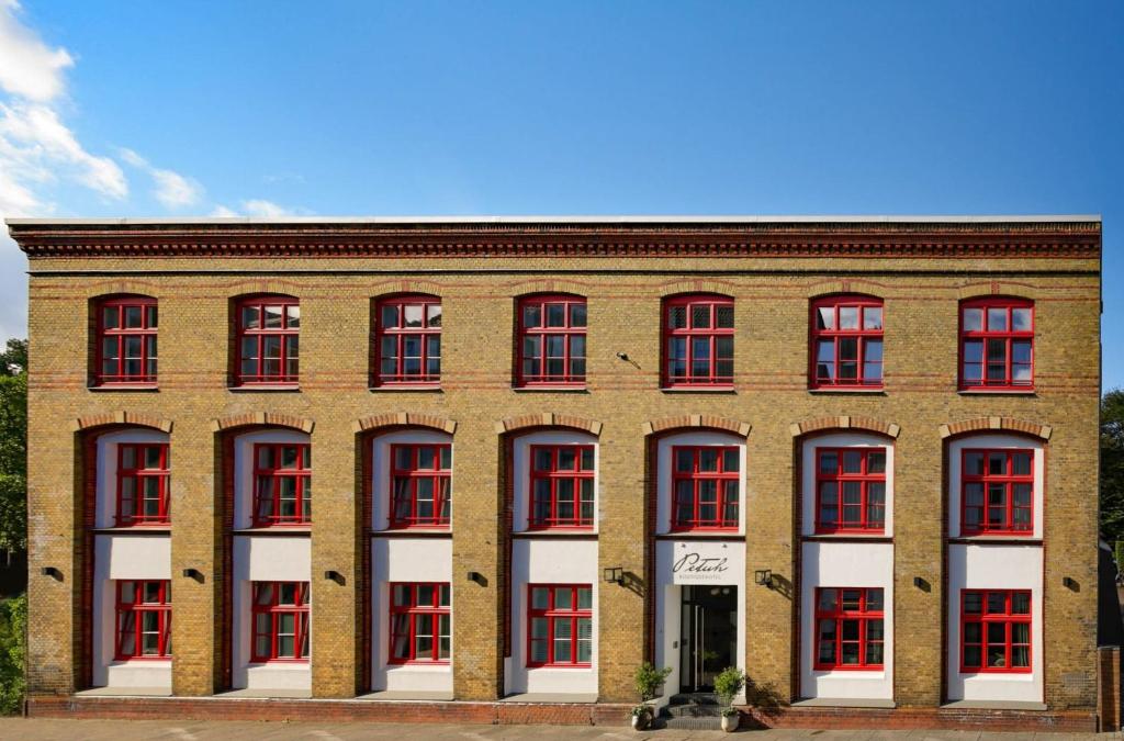 弗伦斯堡Boutiquehotel Petuh的一座大型砖砌建筑,设有红白窗户