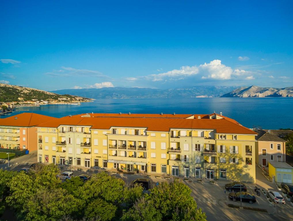 巴斯卡Valamar Atrium Baška Residence的一座有橙色屋顶的建筑,毗邻水体