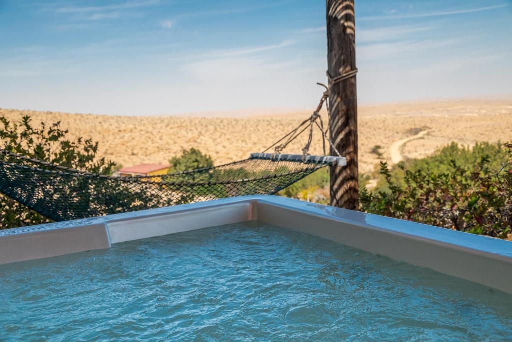 米德希特本-古里安卡梅阿沃達特農場酒店的一个带吊床的游泳池,享有沙漠美景