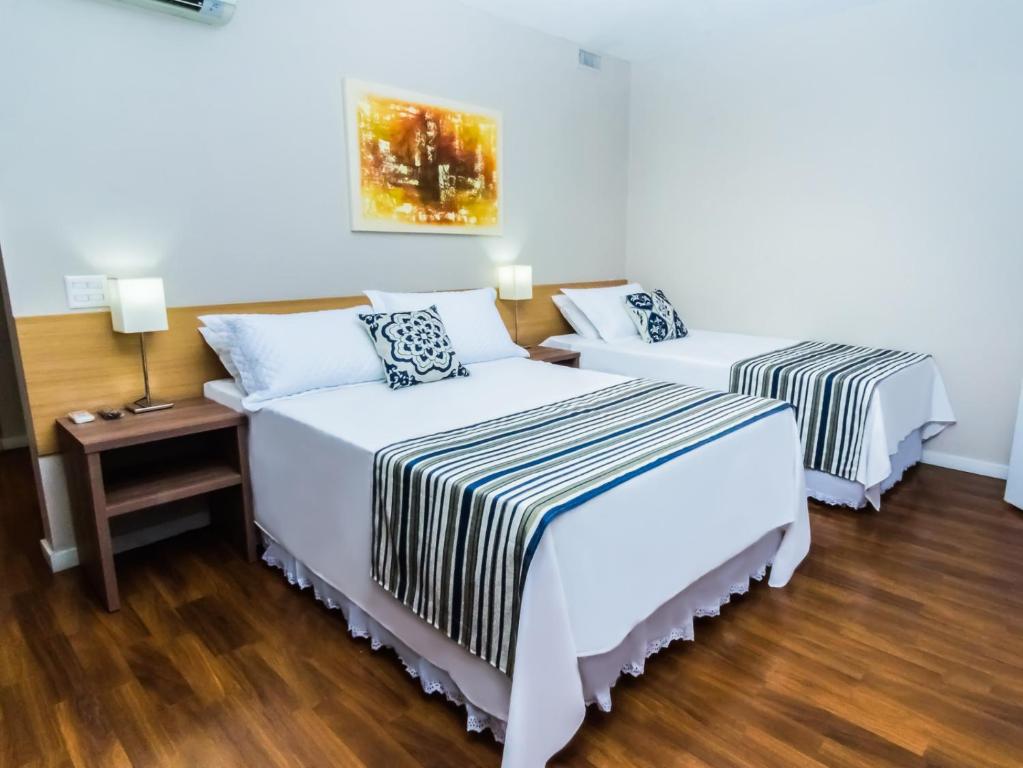 阿雷格里港Hotel Nacional Inn Porto Alegre - Estamos abertos - 200 metros do Complexo Hospitalar Santa Casa的客房设有两张床和一张带台灯的桌子。