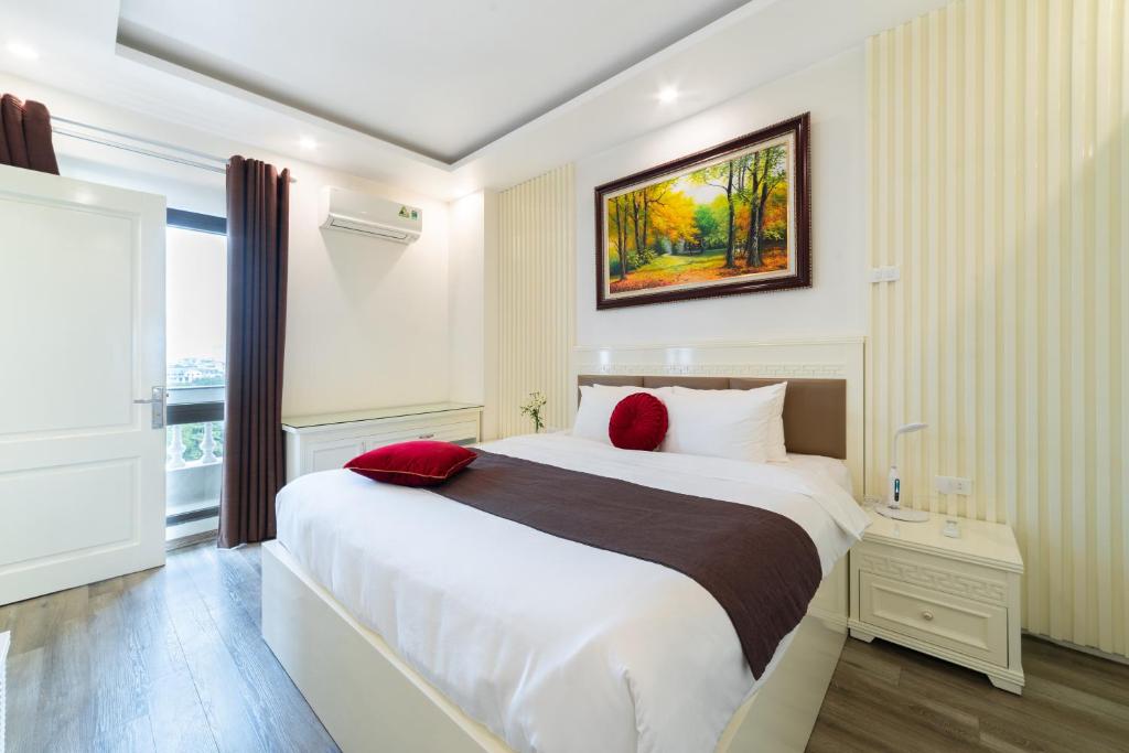河内Rosee Apartment Hotel - Luxury Apartments in Cau Giay , Ha Noi的卧室配有带红色枕头的大型白色床
