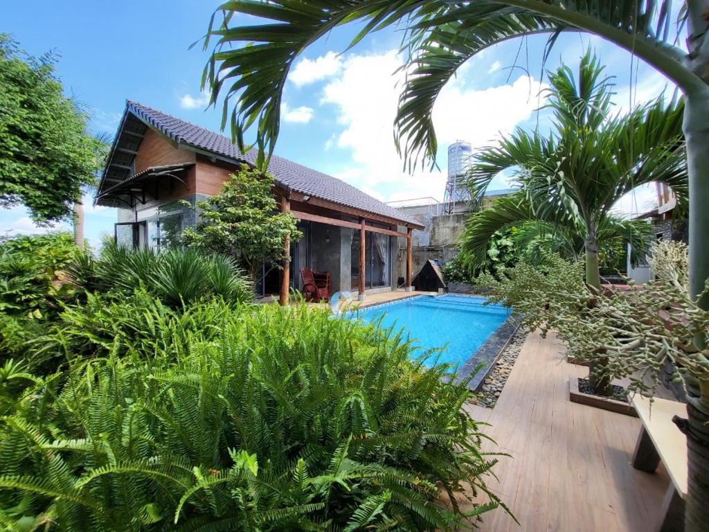 邦美蜀T'Farmstay villa and resort Buon Ma Thuot City的花园中带游泳池的房子