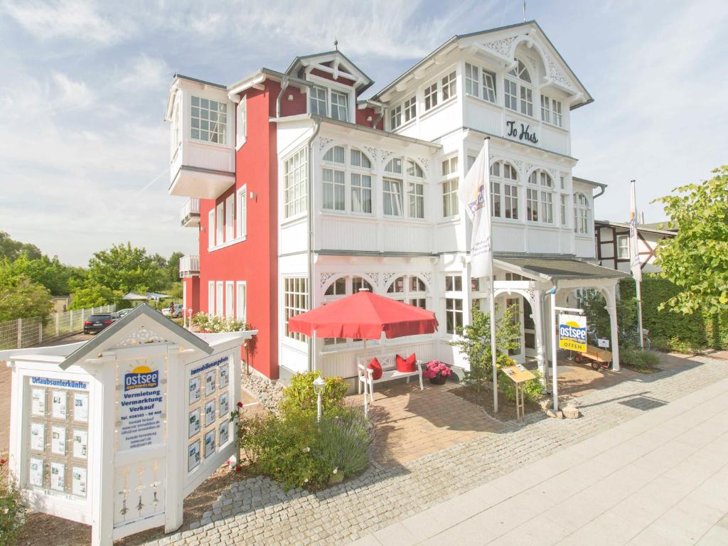 奥斯赛拜-塞林Villa "To Hus" in Sellin - WG 02 mit Kamin und Balkon的一座红色和白色的大建筑,设有庭院