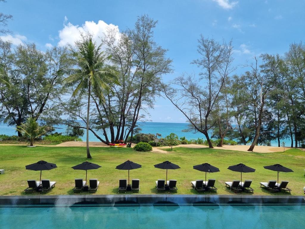 迈考海滩SALA Phuket Mai Khao Beach Resort的一个带椅子和遮阳伞的游泳池以及大海