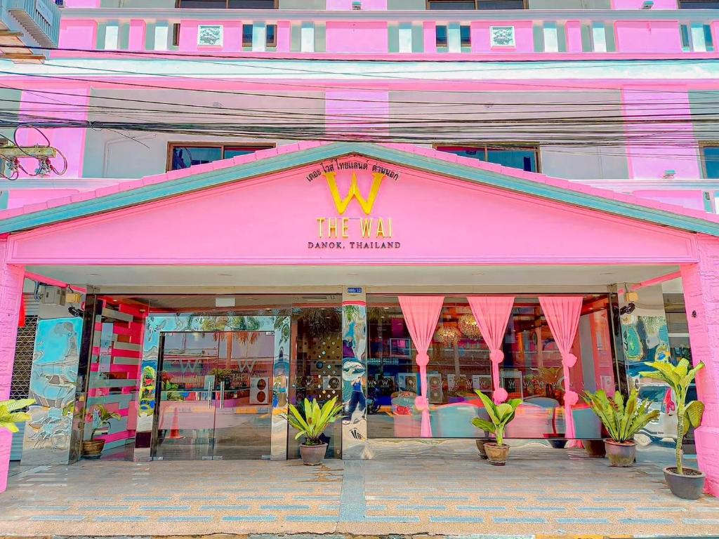 SadaoThe Wai Hotel Danok的前面是粉红色的商店,前面是植物