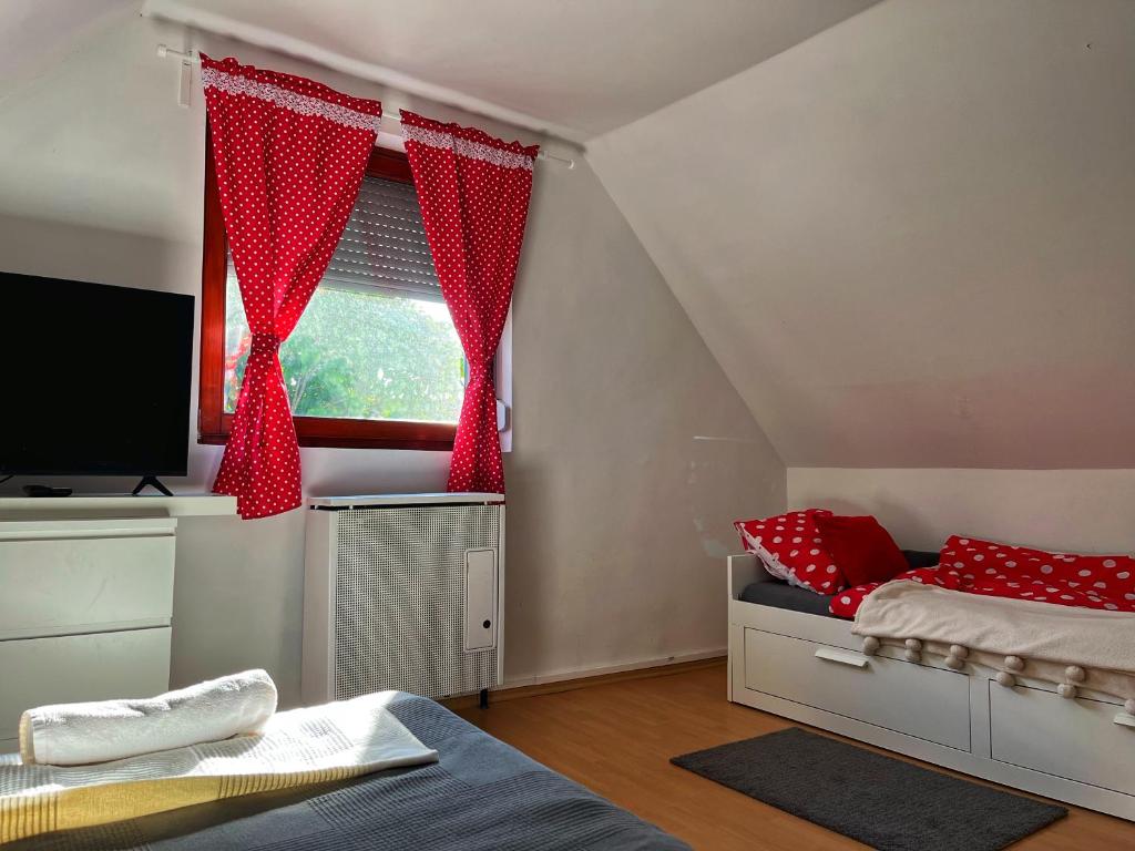 TiszabábolnaPöttyösOtthon Vendégház的一间卧室配有床和红色窗帘的窗户