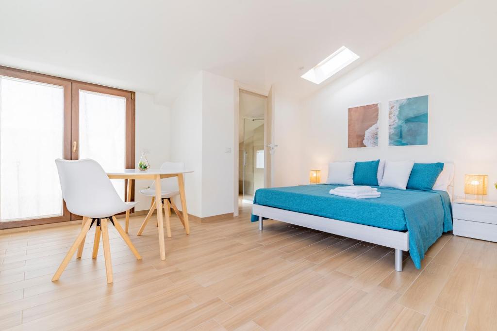 萨萨里Lumen House的白色卧室配有蓝色的床和一张桌子