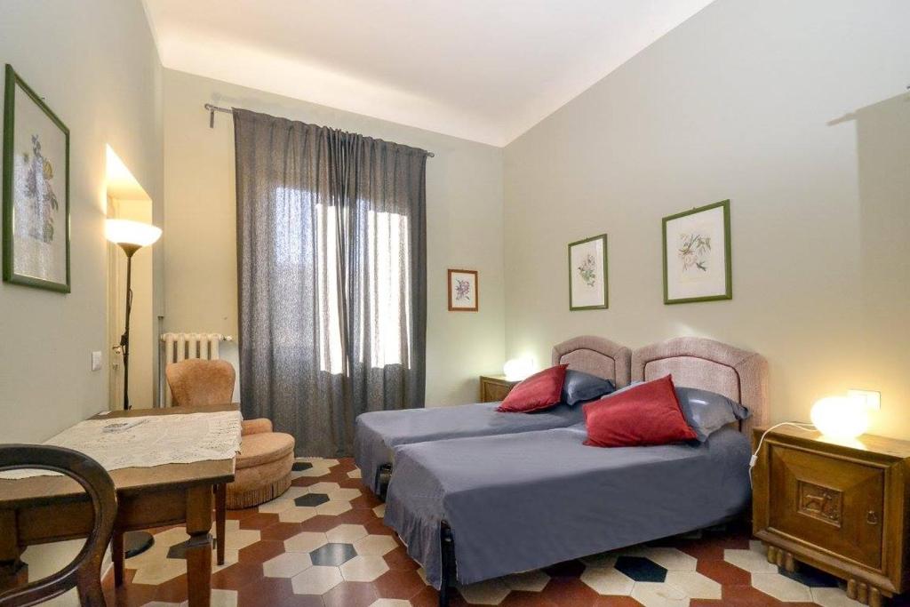佛罗伦萨Palazzo Panzani的一间卧室配有两张床、一张桌子和一把椅子