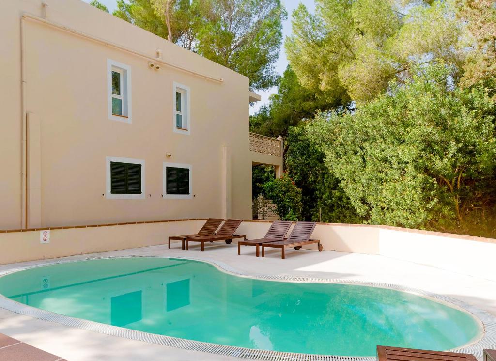 埃斯卡洛Apartamentos El Pino - Formentera Break的一个带两把椅子的游泳池以及一座房子