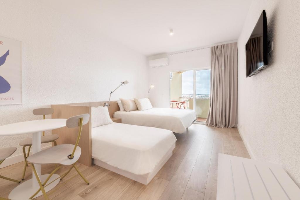 卡斯卡伊斯Equador Superior Suites by Olala Homes的酒店客房设有两张床和一张桌子。