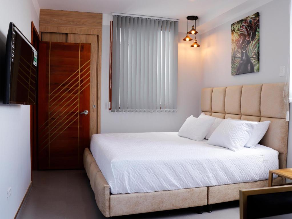 卡塔戈HOTEL GOLDEN CARTAGO的卧室配有带白色床单的床和门。