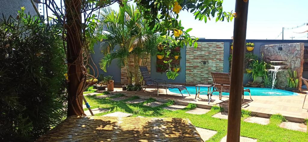 伊瓜苏Pousada Casa Bom Sono的后院设有带长凳和树木的游泳池