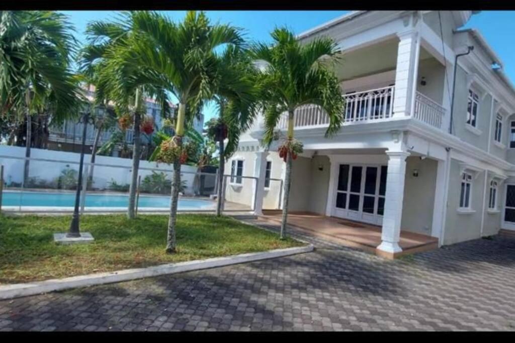 佩雷贝勒Villa Palmira 6 suites avec piscine 5 min à pied de la plage Pereybere的一座种植了棕榈树和游泳池的大型白色房屋