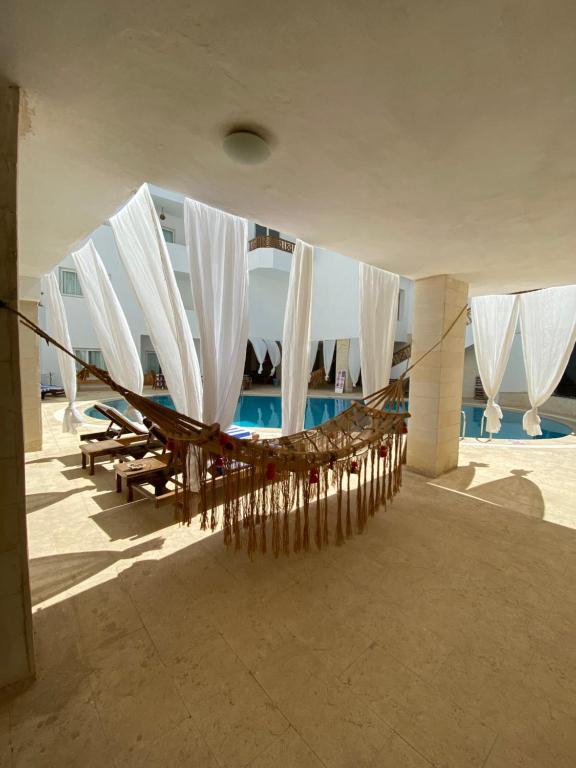 马萨阿拉姆蓝色视觉潜水住宿加早餐旅馆的游泳池畔的吊床上配有白色遮阳伞