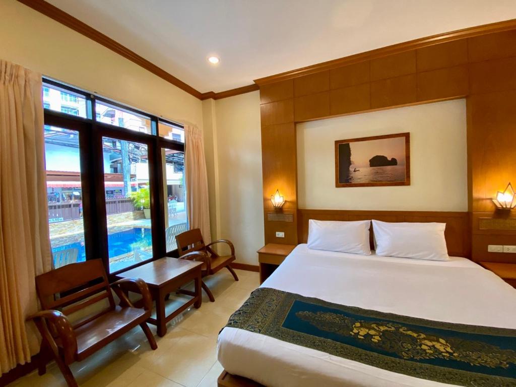 芭东海滩Baan Sudarat Hotel的卧室配有床、椅子和窗户。