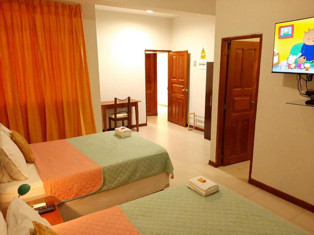 伊基托斯100 RV Apartments Iquitos-Apartamento primer piso con vista a piscina的酒店客房设有两张床和一台平面电视。