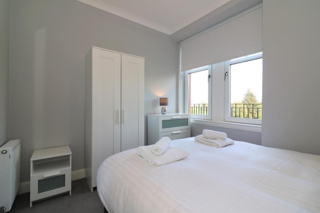 格拉斯哥Signature - Greenlees Clubhouse的白色卧室配有一张大床和两条毛巾