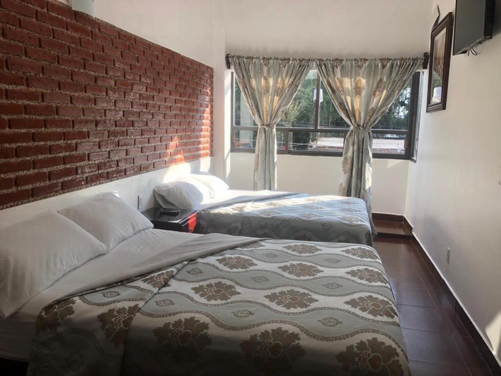 圣胡安特奥蒂瓦坎Hotel CALLI YOLOTL Teotihuacan的一间卧室设有两张床和砖墙